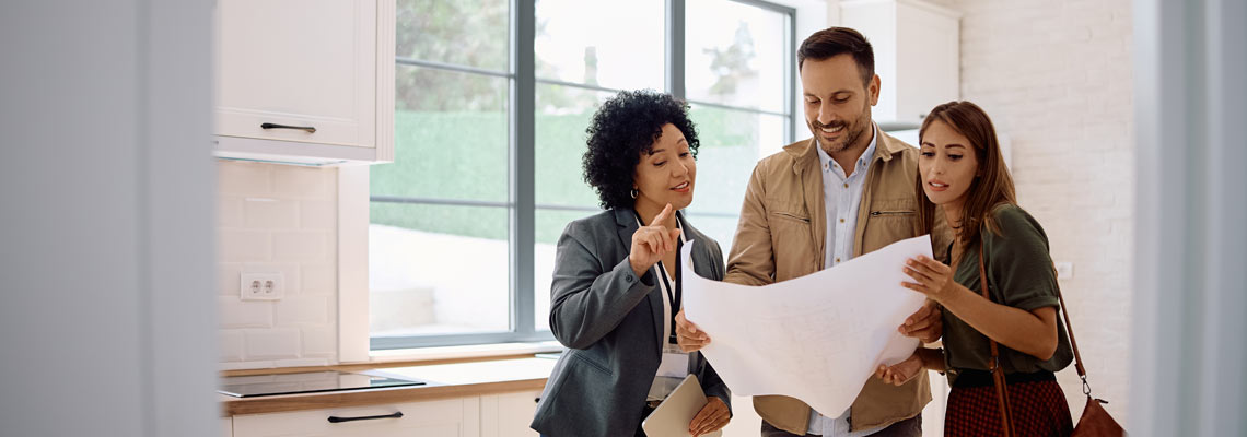 Real estate agent and a couple looking at blueprints of a new house