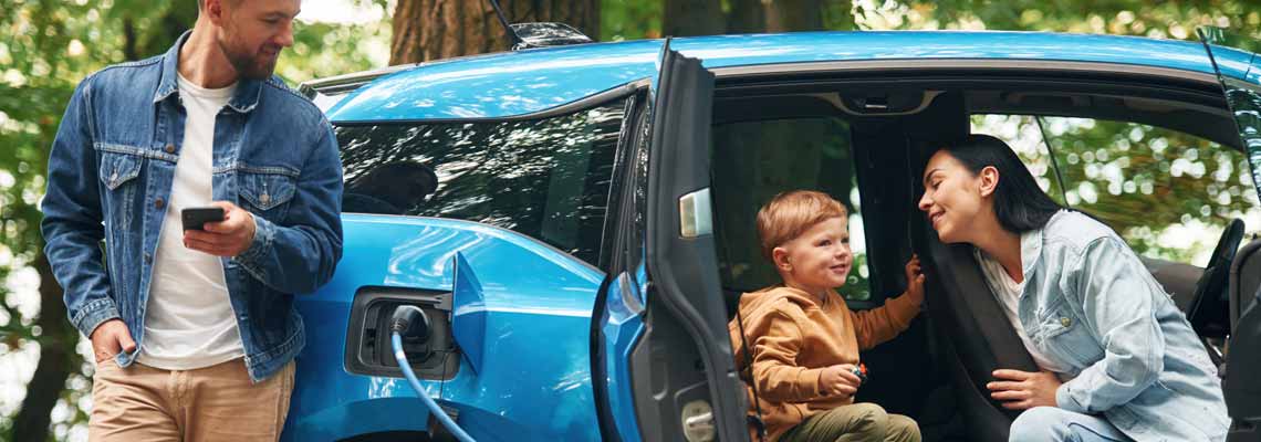 Mother, father and little son are waiting for electric car to charge outdoors