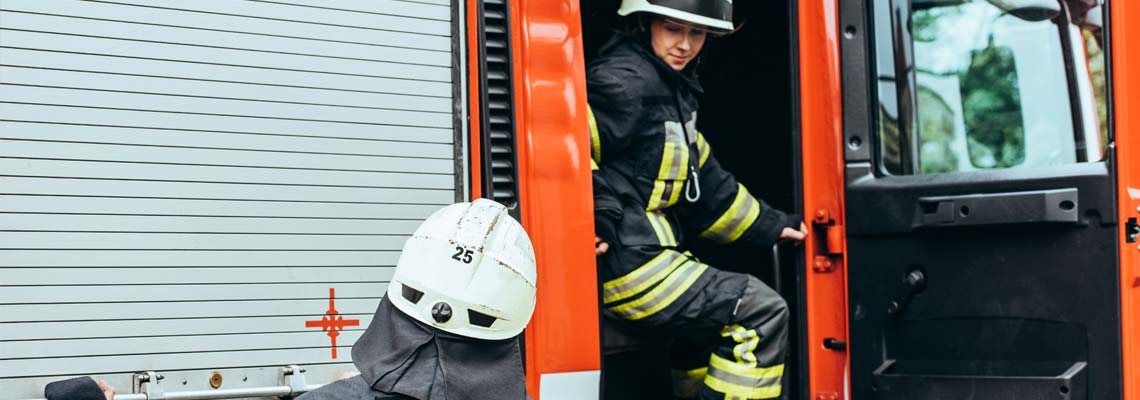 firefighters in helmets at fire truck on street