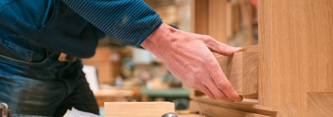 Close up of carpenter in workshop gluing wood to window frame