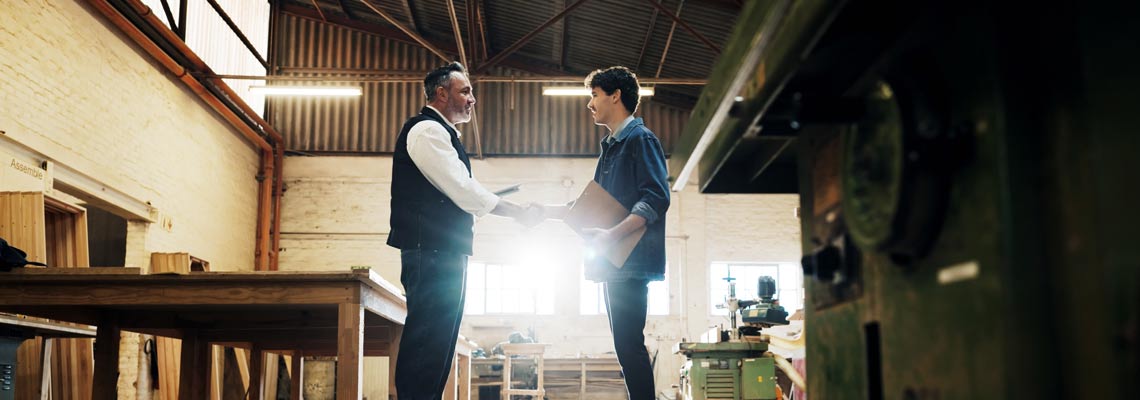 Inspector and carpenter shaking hands in a warehouse