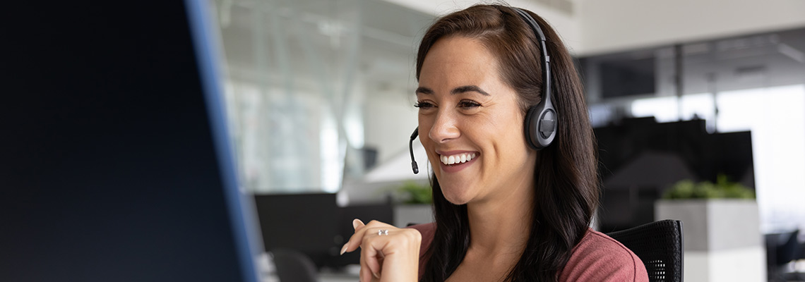 Smiling woman wearing a headset on the phone with a customer