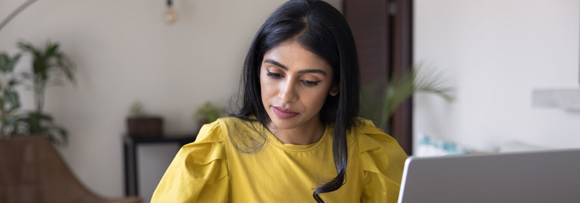 woman sitting at desk with laptop, using calculator
