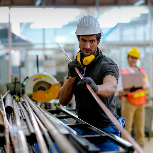 Factory worker  with safety helmet holding copper tube