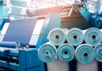 Rolls of industrial cotton fabric for clothing, cloth textile manufacture on machine.