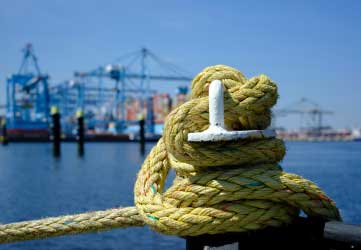 An iron bollard with a tied rope on a quay in the Port