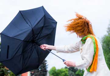 A woman tries to hold her umbrella in a strong wind