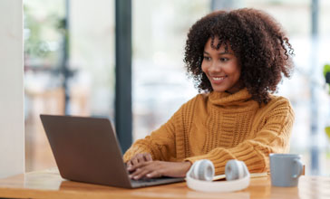 young African American woman using laptop in coffee shop
