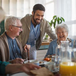 Group of cheerful seniors enjoying breakfast in nursing home care centre