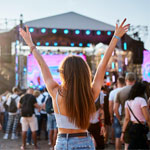Back view of girl with raised arms, enjoying live music