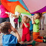 Children playing under a rainbow parachute