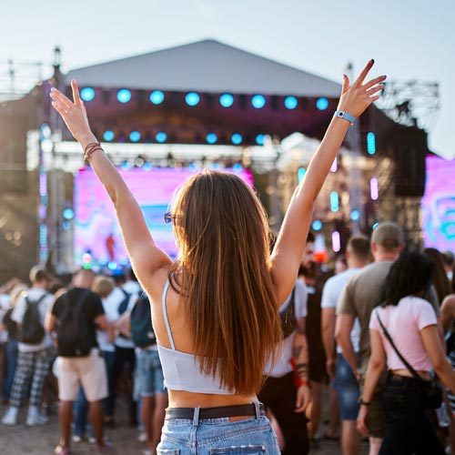 Back view of girl with raised arms, enjoying live music