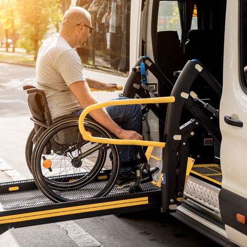 A man in a wheelchair on a lift of a vehicle for people with disabilities