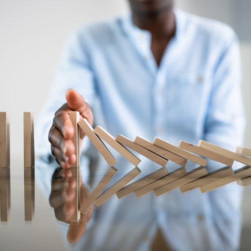 African American businessman stopping dominos from falling