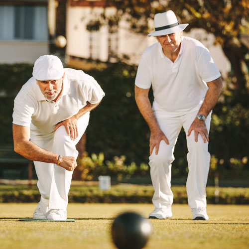 Two senior men playing boules in a park.