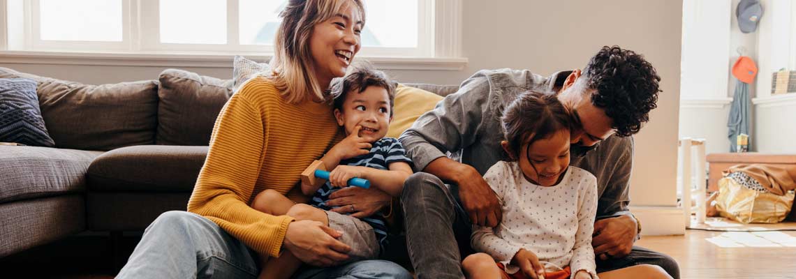 Young parents playing with their son and daughter in the living room