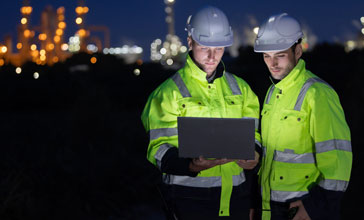 Petroleum engineers with hardhat working at oil refinery site at night