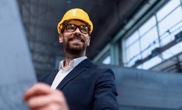 Portrait of engineer with protective helmet holding floor plans