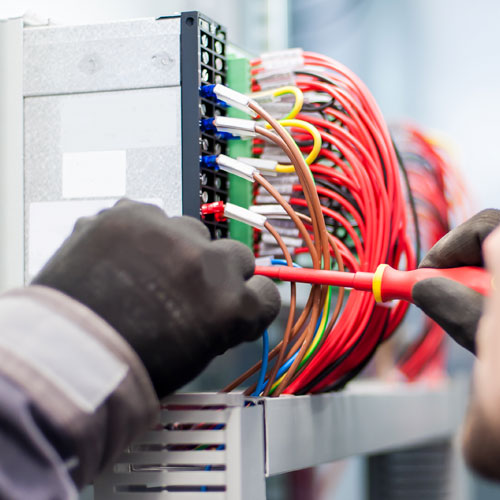 Closeup of electrician working with electric cable wires of fuse switch box