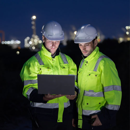 Petroleum engineers with hardhat working at oil refinery site at night
