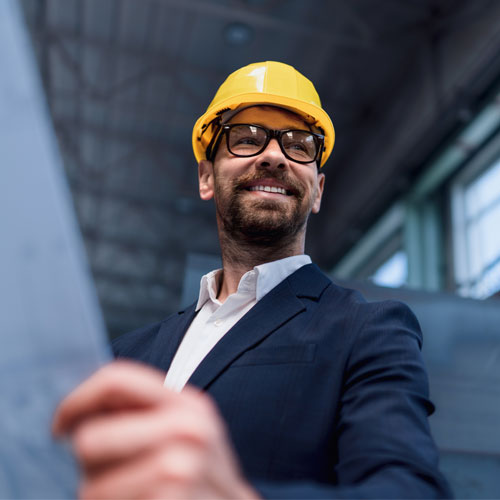 Portrait of engineer with protective helmet holding floor plans