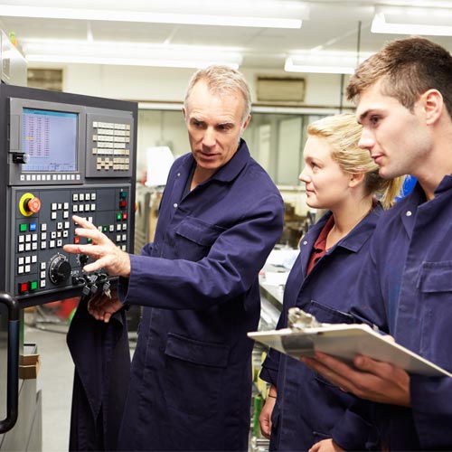 Engineer teaching apprentices to use computerized lathe