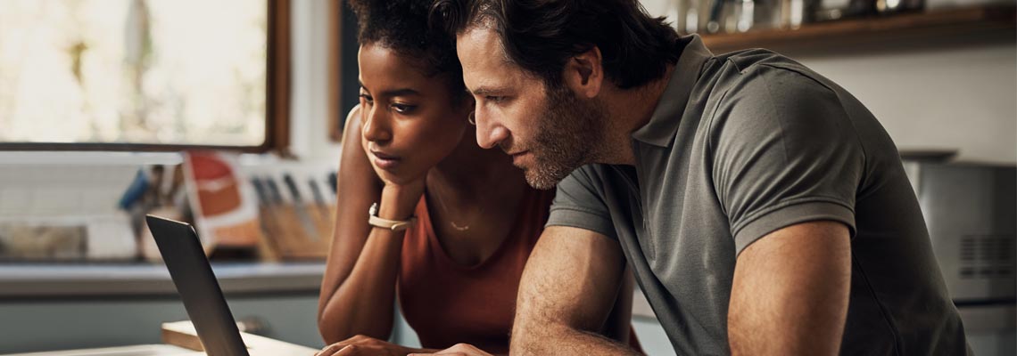 Couple looking at laptop screen in the kitchen