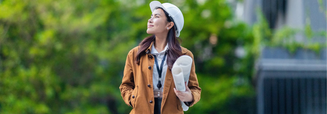 Female architect with hardhat holds blueprints