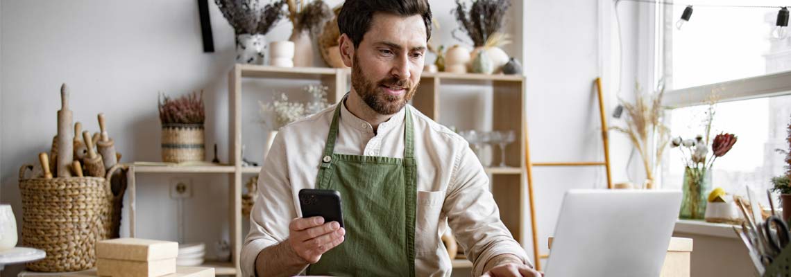 store employee using laptop and smartphone