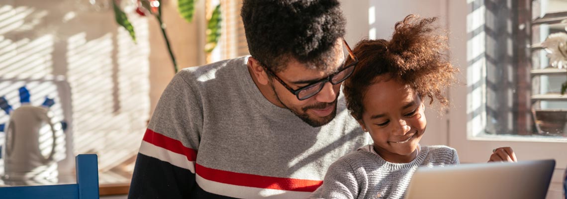 father and daughter looking at laptop