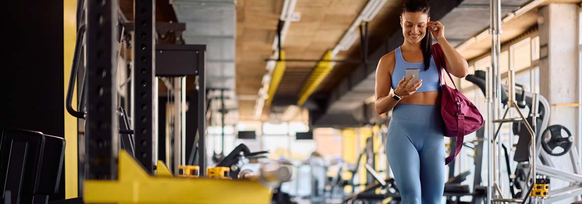 Happy athletic woman adjusting her earbuds at the gym