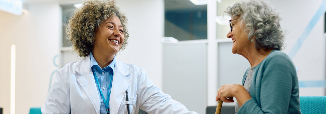 Happy doctor and her senior patient talking in waiting room