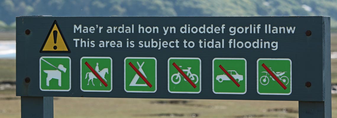 Bilingual sign warning in English and Welsh warning of tidal flooding