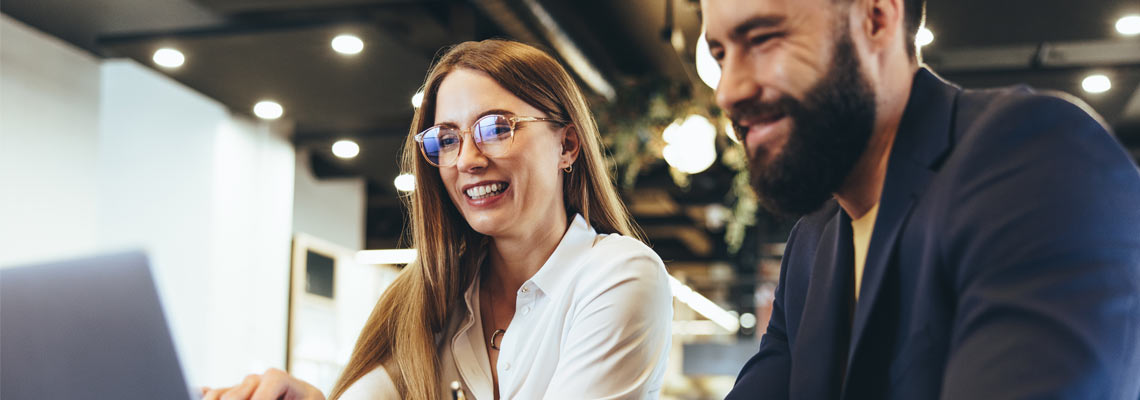 Two businesspeople using a laptop in an office