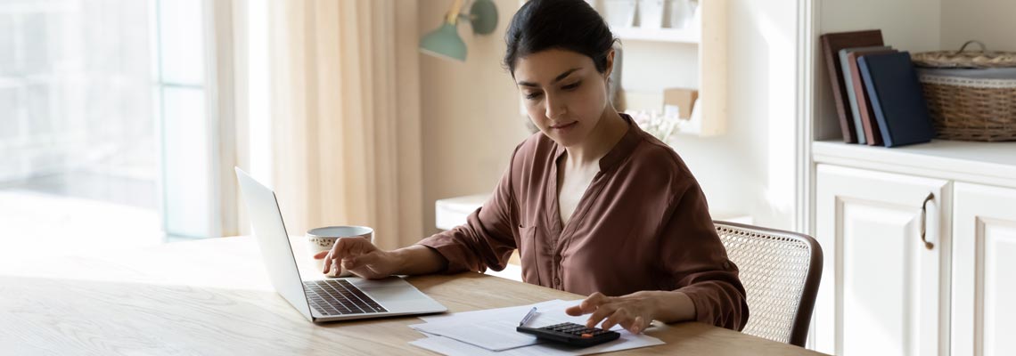 Serious Indian housewife sit at table pay bills