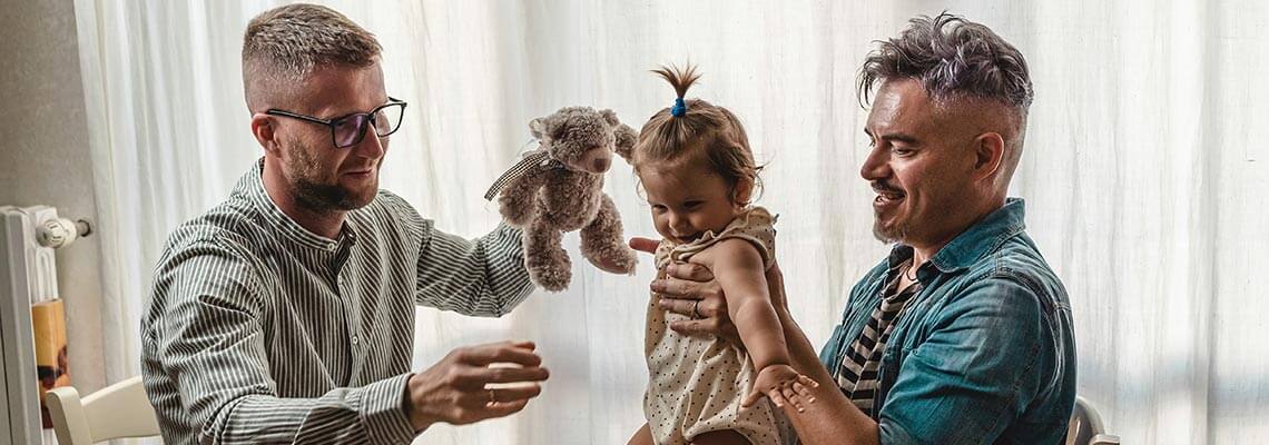 Two dads playing with their baby