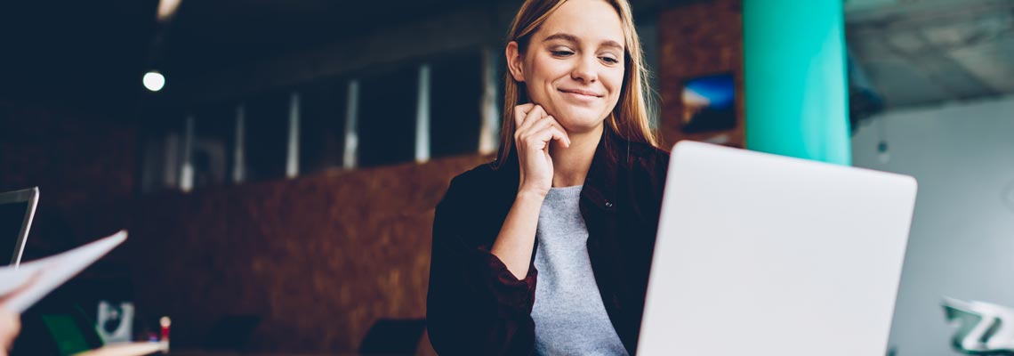 Positive student with blonde hair reading business news on netbook
