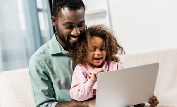 father and young daughter using laptop