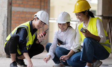 young group of people in hard hats looking at plans