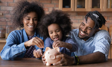 young family putting money into a piggy bank