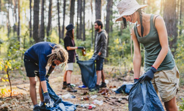 Group of volunteer people picking up plastic in forest