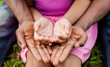 child's hands on top of parent's hands