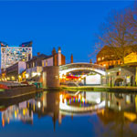 The cube behind brick buildings alongside a water channel in the central Birmingham