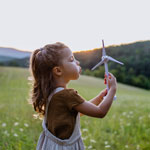 Little girl standing in fields with model of wind turbine