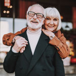 happy lady hugging husband from behind while he is holding her hand