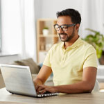 man in yellow top using laptop