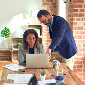 Two middle age business workers working together using laptop at the office