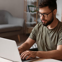 Man in wheelchair using laptop at home
