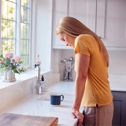 sad woman looking at the kitchen sink