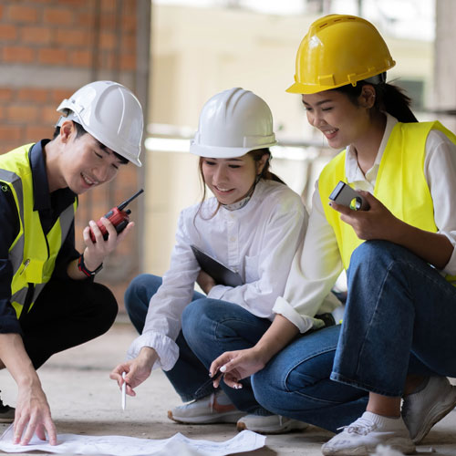 young group of people in hard hats looking at plans